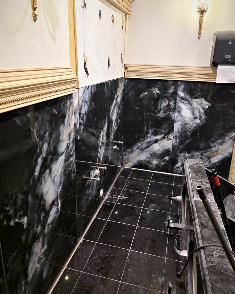 Commercial washroom wainscot and floor in polished black marble tile