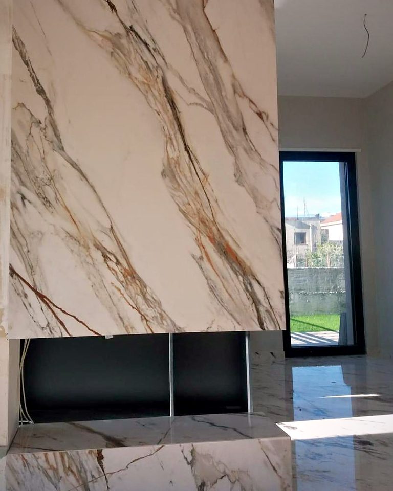 Floor-to-ceiling large-format marble-look porcelain slab fireplace with a linear firebox