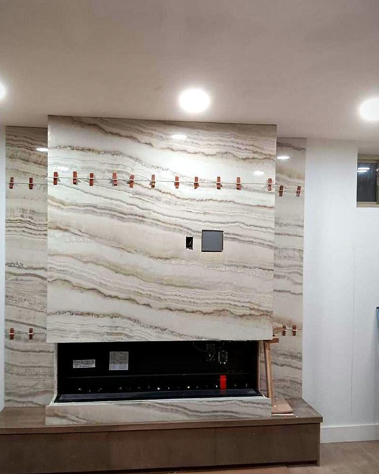 Onyx-look porcelain slab feature wall with a wide linear fireplace and floating hearth bench