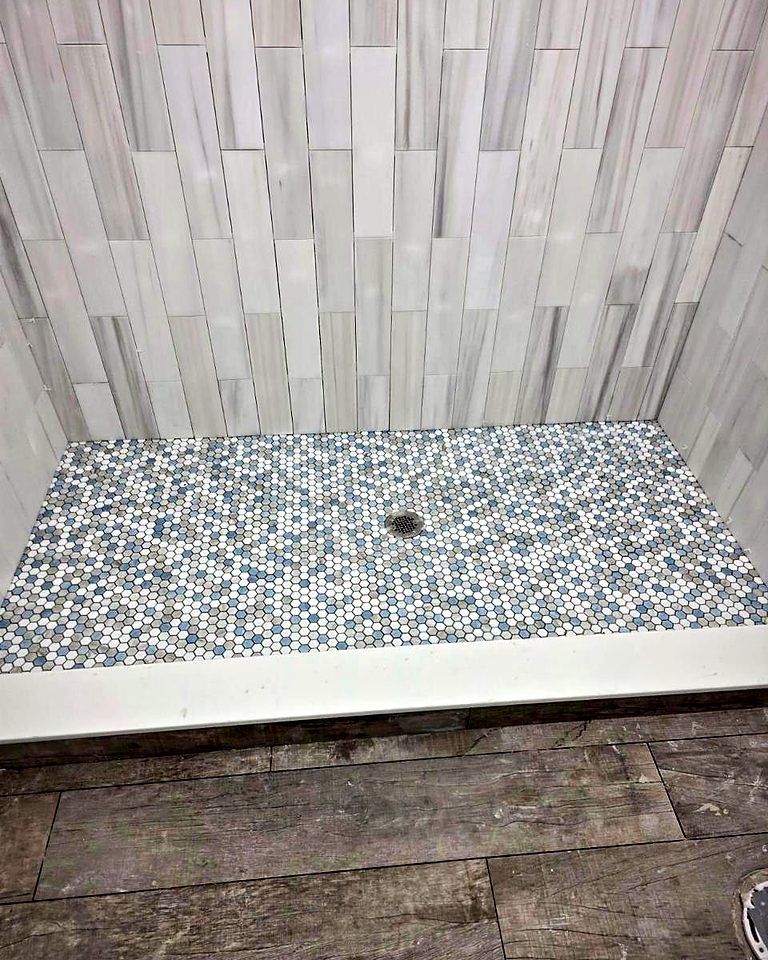 Shower with vertical white stacked tile walls and a blue-grey penny tile floor