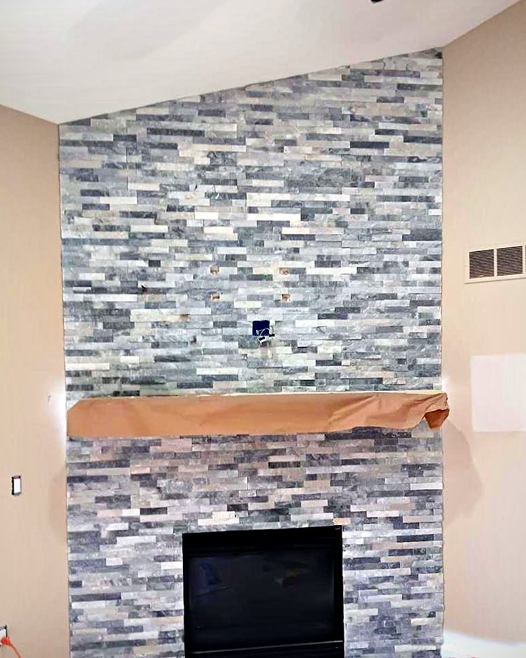 Vaulted-ceiling fireplace in grey stacked ledger stone with a wood mantel